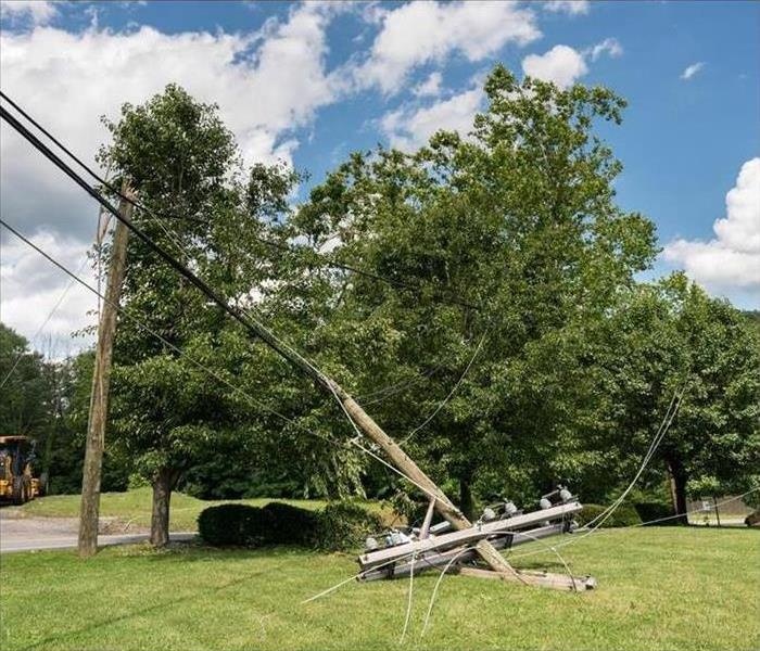 Fractured timber power line bridge with electrical components on the ground after a storm.